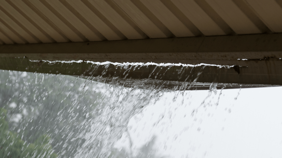 Rain water bursts from the cracked sides of an old gutter 980x551