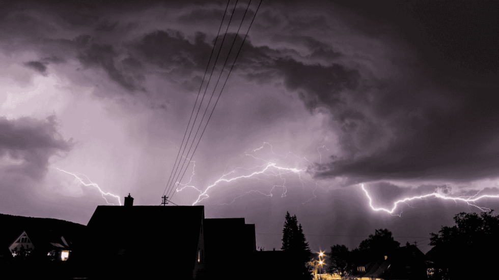 A dark sky is illuminated by a large streak of lightning 980x551