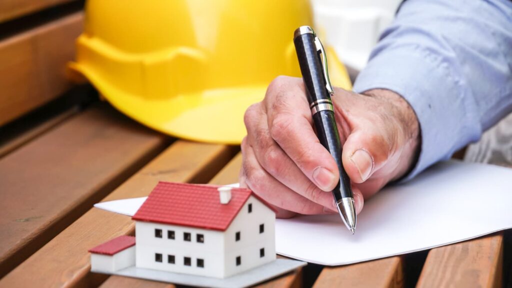 A model home sits on a bench next to a contract being signed.