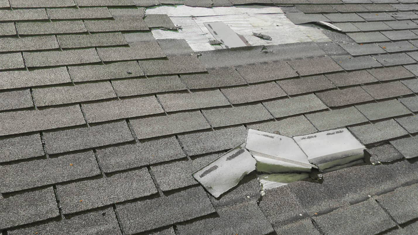 A roof with multiple missing or broken asphalt shingles