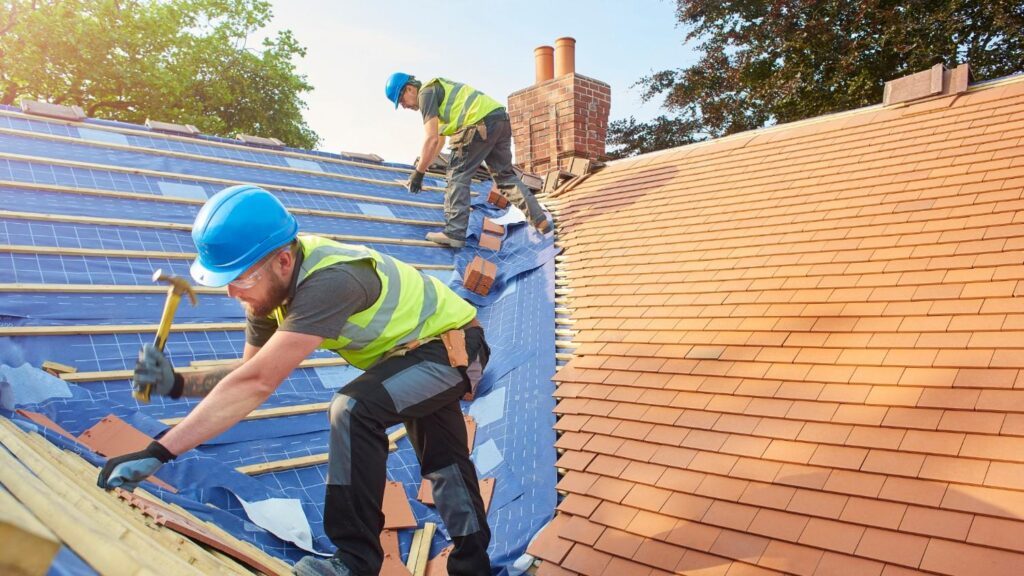 A team of roofers install eco friendly clay roofing tiles.