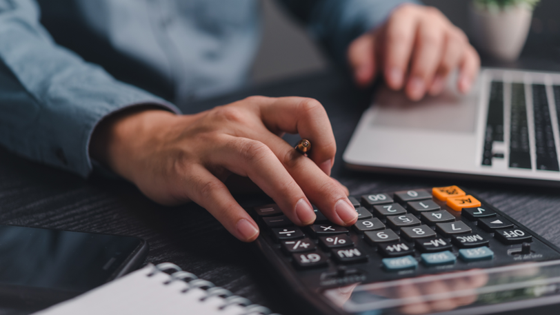 A business owner uses a calculator while budgeting.