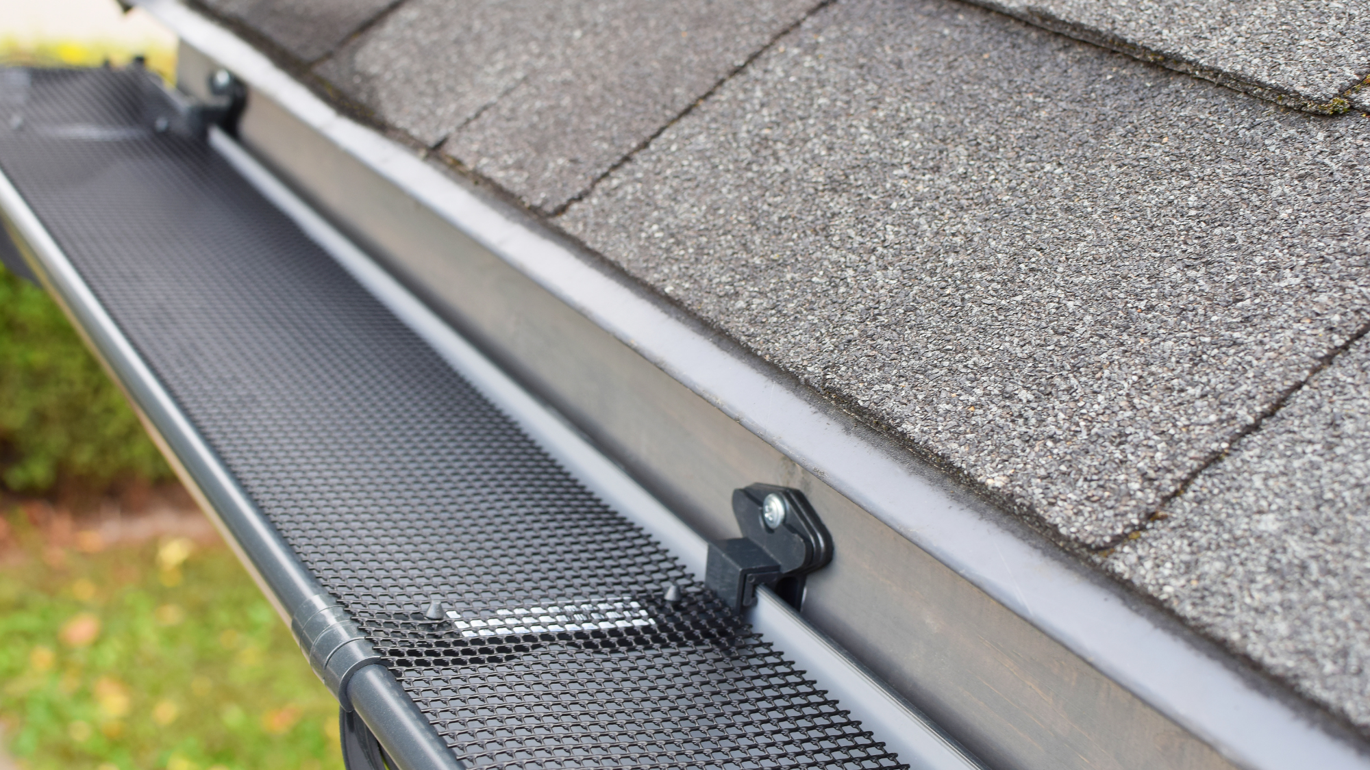 A roof with asphalt shingles and gutters that are sealed with screens to keep out debris.